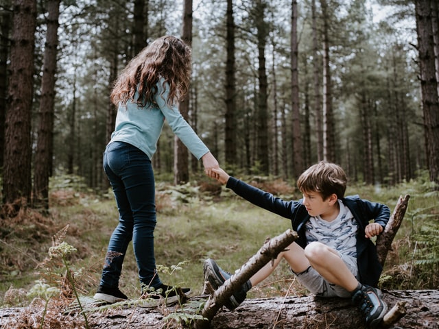 Childs helping each other. Girl helps boy getting up the floor