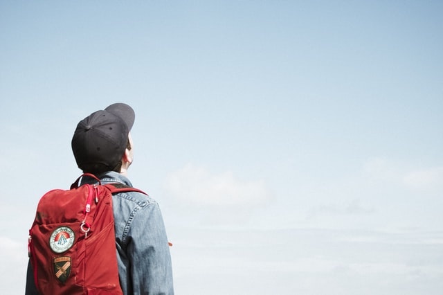 regreso a clases presenciales niño con mochila mirando al cielo